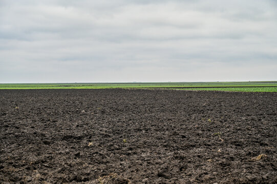 Freshly plowed field ready for seeding and planting. Empty plowed land in Romania. Black soil.