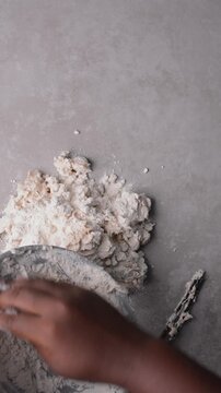 Overhead view of scallion pancake dough being poured on a grey countertop, top view of cong you bing dough being mixed, process of making scallion pancakes