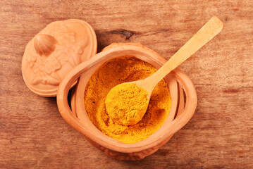 Dry curry powder in bowl on wooden table