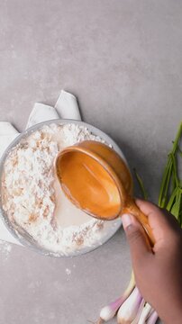 Overhead view of water being added to flour to make scallion pancake dough, top view of cong you bing dough being mixed, process of making scallion pancakes
