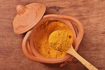 Dry curry powder in bowl on wooden table