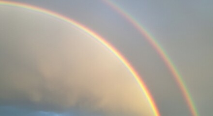 Vibrant double rainbow arching gracefully across a softly lit cloudy sky after a cleansing rain a stunning natural spectacle. AI Generated