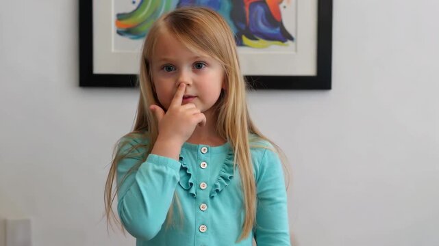 Blonde little girl makes boo gesture indoors