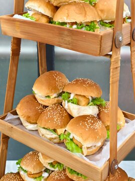 Close-up of Gourmet Mini Chicken Sliders Description: High-angle close-up of delicious mini sliders featuring breaded chicken patties, sesame seed buns, and fresh greens, perfect for tea time or parti