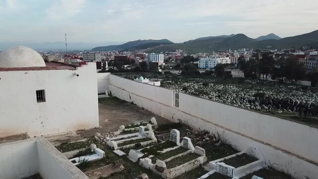 Drone shot overlooking the courtyard of a traditional white Islamic shrine (Marabout), showing ancient graves enclosed within the white walls in Morocco.