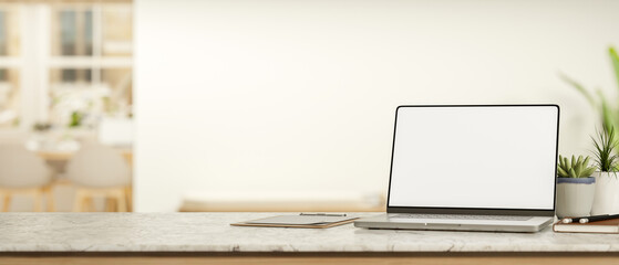 White screen laptop with book and clipboard on marble counter table across white wall in living room