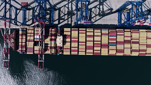 Top-down drone shot of cargo ship and cranes at Port of Gdańsk, Baltic Sea