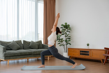 Young Asian woman stretching yoga workout on exercise mat in living room at home