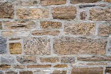 Natural stone wall texture with rough masonry blocks and visible mortar. Neutral rocky surface background suitable for architecture, construction, and design projects.
