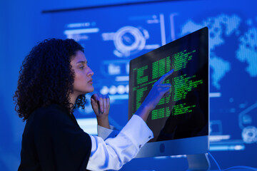 Young woman analyzes data on computer screen in a high-tech office setting during the evening hours