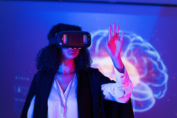 Woman in virtual reality headset interacts with brain imagery in a modern tech space during an immersive experience