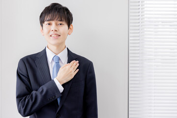 胸に手をあてる若いビジネスマン