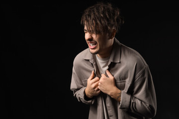 Young man having panic attack on black background