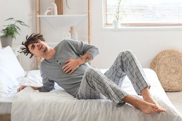 Young man having panic attack on bed at home