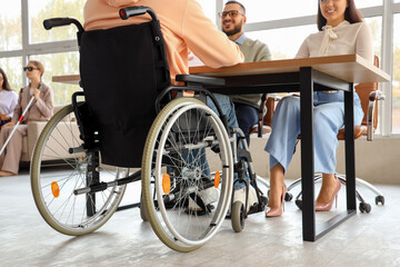Obraz premium Male applicant in wheelchair with human resources commission during job interview at office, back view