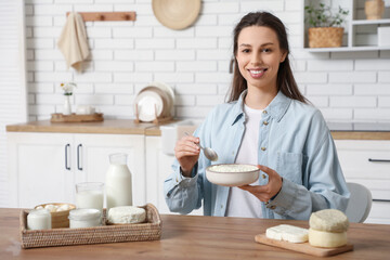 Young woman with different dairy products at table in kitchen