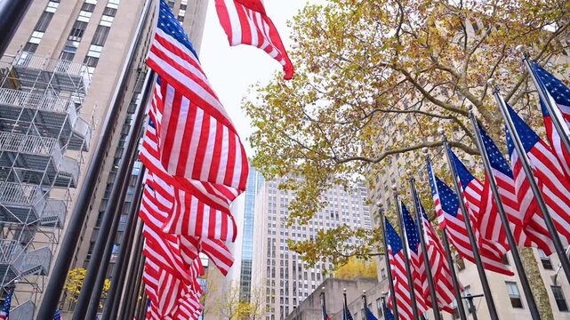 American flags across Rockefeller buildings. American flags stretch above the plaza surrounded by tall Rockefeller Center buildings.