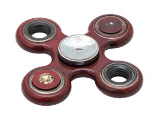 A close-up studio shot showcases a four-leaf clover shaped handheld spinning toy with a central cap. Metallic and wood grain appearance