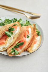 Crepes or thin pancakes with lightly salted salmon, soft cheese and cornsalad