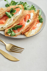 Crepes or thin pancakes with lightly salted salmon, soft cheese and cornsalad