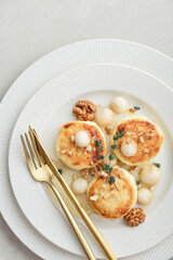 cottage cheese pancakes, syrniki, curd fritters served with pear balls, walnut and honey