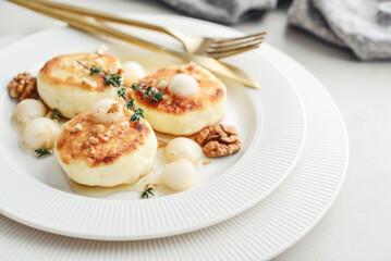 cottage cheese pancakes, syrniki, curd fritters served with pear balls, walnut and honey