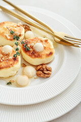cottage cheese pancakes, syrniki, curd fritters served with pear balls, walnut and honey