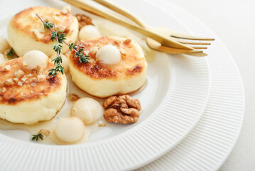 cottage cheese pancakes, syrniki, curd fritters served with pear balls, walnut and honey