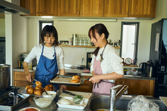 キッチンで焼き上がった手作りパンを確認する女性達