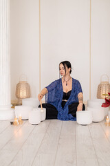 Healing meditation. Sound therapy. Woman playing crystal singing white bowls wellness retreat steam fire candles for spiritual treatment.