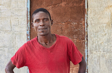 village happy african man portrait, outdoors in the nature ,stone wall with door behind