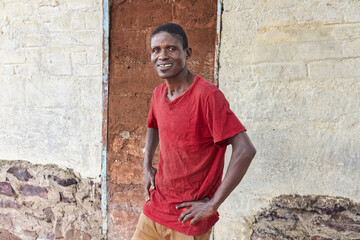 village happy african man portrait, outdoors in the nature ,stone wall with door behind