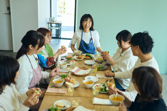 料理教室の後作った料理を囲んで食事を楽しむ人々
