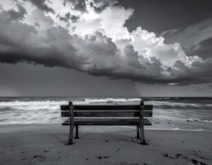 Black and white image of a beach with a bench and dark sky
