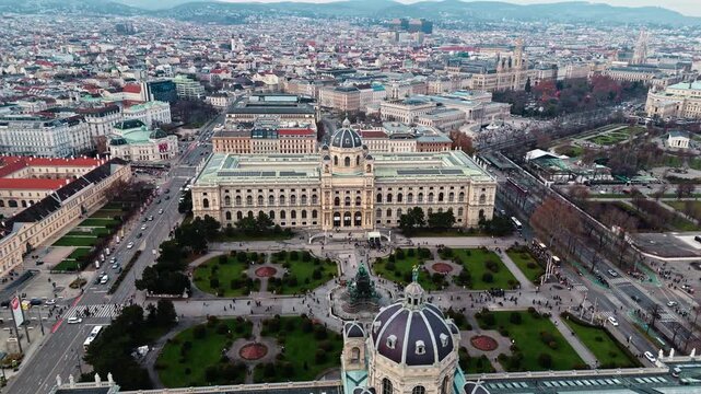 Aerial drone shot panning left over the Austrian Natural History Museum in Vienna, highlighting its grand fa&ccedil;ade and surrounding city streets under clear winter sunlight.