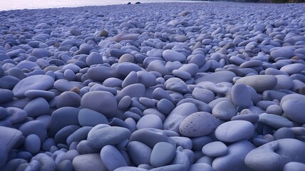 Obraz premium Wide view of smooth blue pebbles covering natural ground 