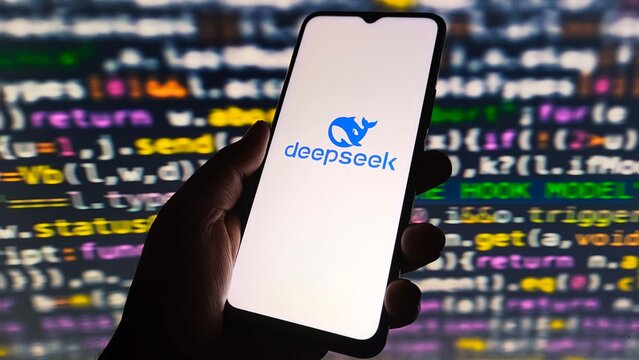 Hand holding smartphone displaying deepseek logo against a background of colorful programming code