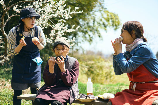農作業の合間に畑で昼食のおにぎりを食べる女性達