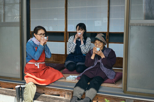 日本の縁側でおやつを食べながら休憩する
三世代の女性達