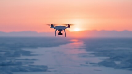 A drone hovers above icy terrain, capturing stunning views of a vibrant sunset reflecting over the landscape.