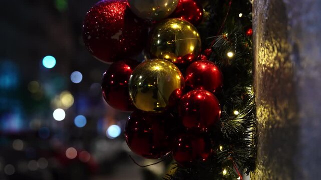 Shiny round Christmas tree ornaments displayed as part of a luxury boutique entrance decoration on a city street, creating an elegant and festive holiday atmosphere.