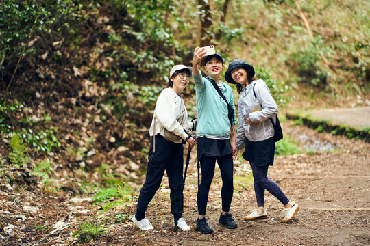 森林のハイキングコースで写真撮影を楽しむ女性グループ