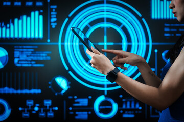 Woman holding tablet computer with futuristic blue data dashboard background, digital analytics, smart technology, data visualization, business intelligence, advanced user interface design.