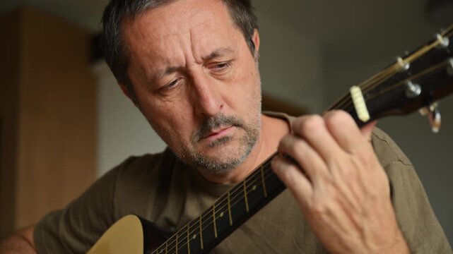 Amateur musician practicing and learning to play acoustic guitar at home, casual lifestyle and creativity concept. 4K.