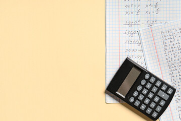 Copybook with handwritten maths formulas and calculator on yellow background