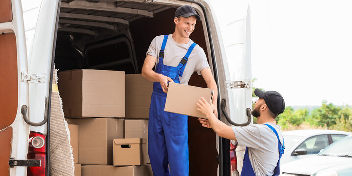 Male movers unloading box from car outdoors