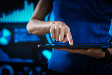 Woman holding tablet computer with futuristic blue data dashboard background, digital analytics, smart technology, data visualization, business intelligence, advanced user interface design.