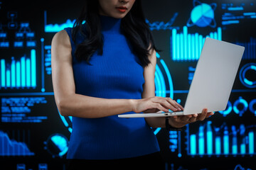 Professional woman working on laptop with futuristic data visualization background, representing digital analytics, business intelligence, productivity, advanced computing in high tech environment.