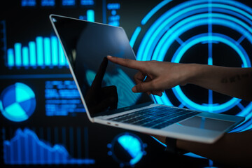 Professional woman working on laptop with futuristic data visualization background, representing digital analytics, business intelligence, productivity, advanced computing in high tech environment.