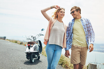 Fototapeta premium Couple, holding hands and walk on road trip by ocean, scooter and conversation with love, sunglasses and holiday. Man, woman or smile for bonding, outdoor and travel with space on summer vacation
